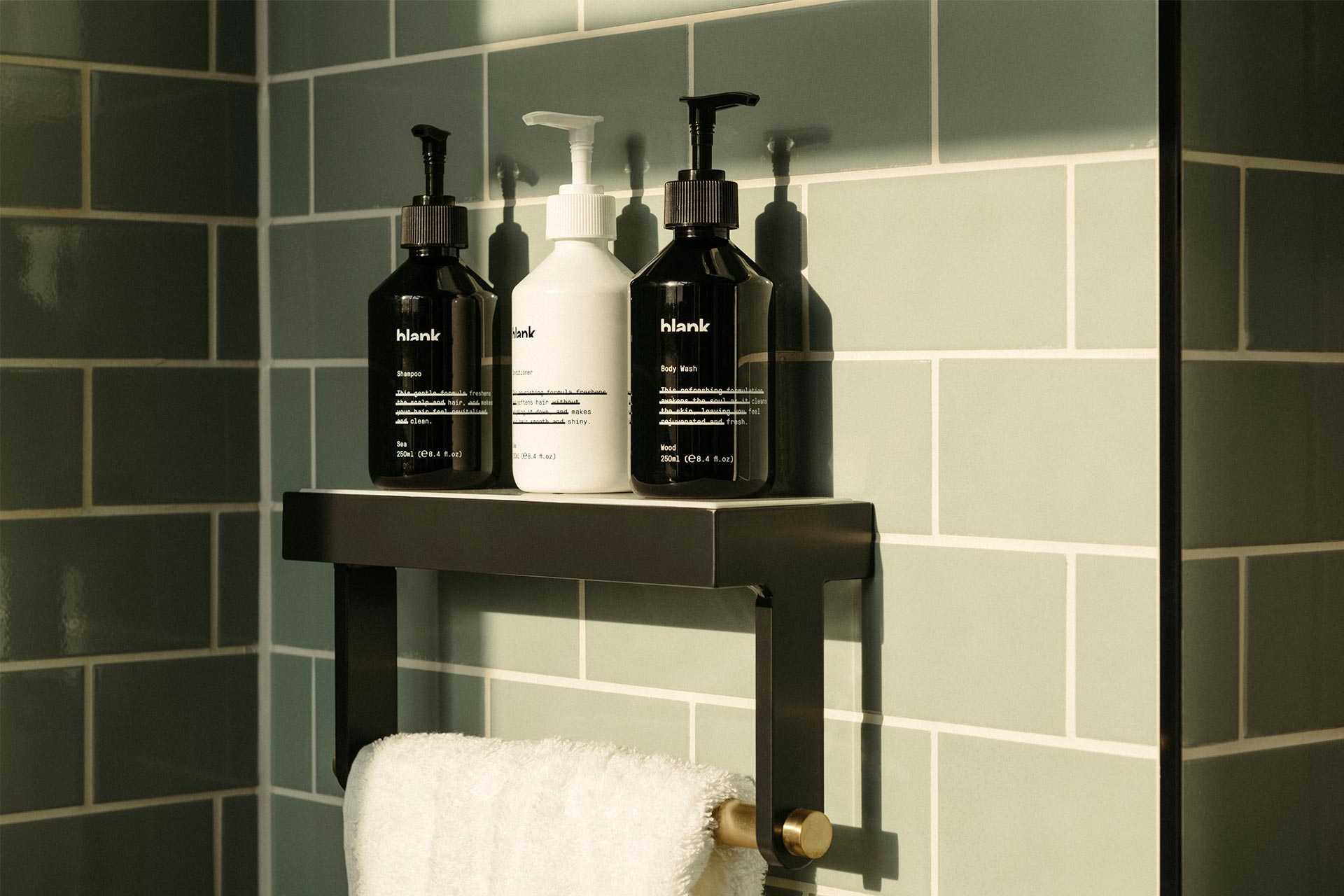 Blank products of Shower Gel, Shampoo and Conditioner sitting above a towel rail