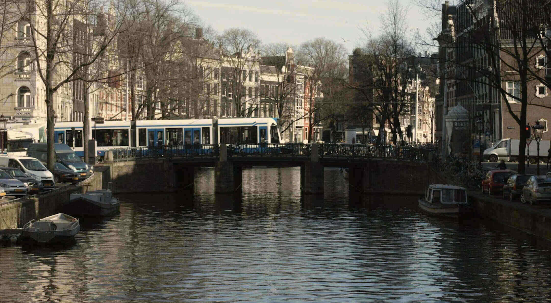 Amsterdam canal with tram going across bridge