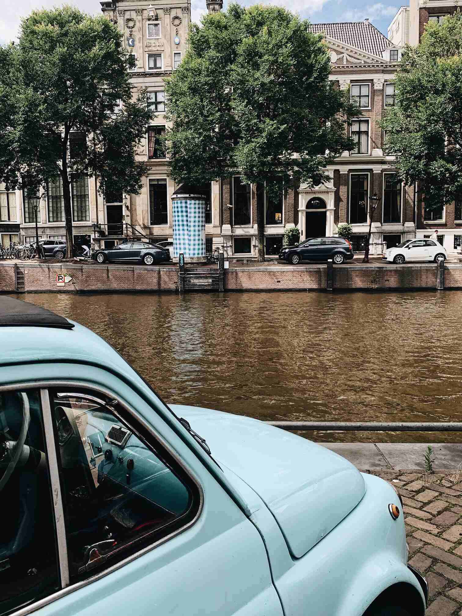 Amsterdam Canal Houses with light blue car in foreground