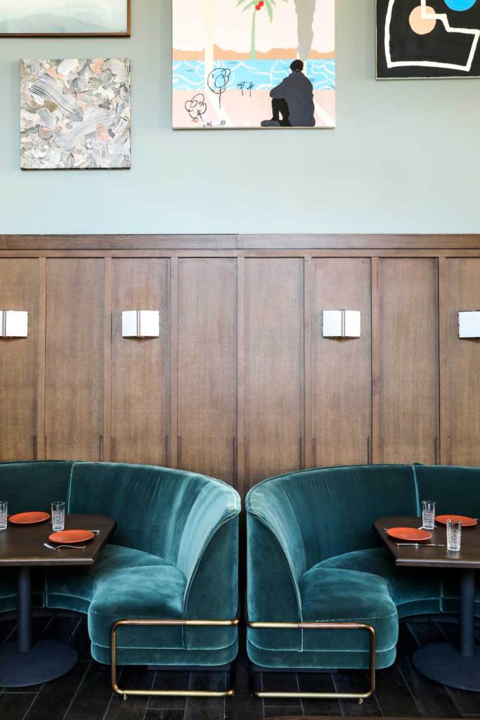 Circular velvet seating booths along a wall covered in artwork