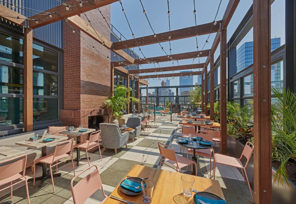 A large sunny outside terrace with lots of seating and city views in the background