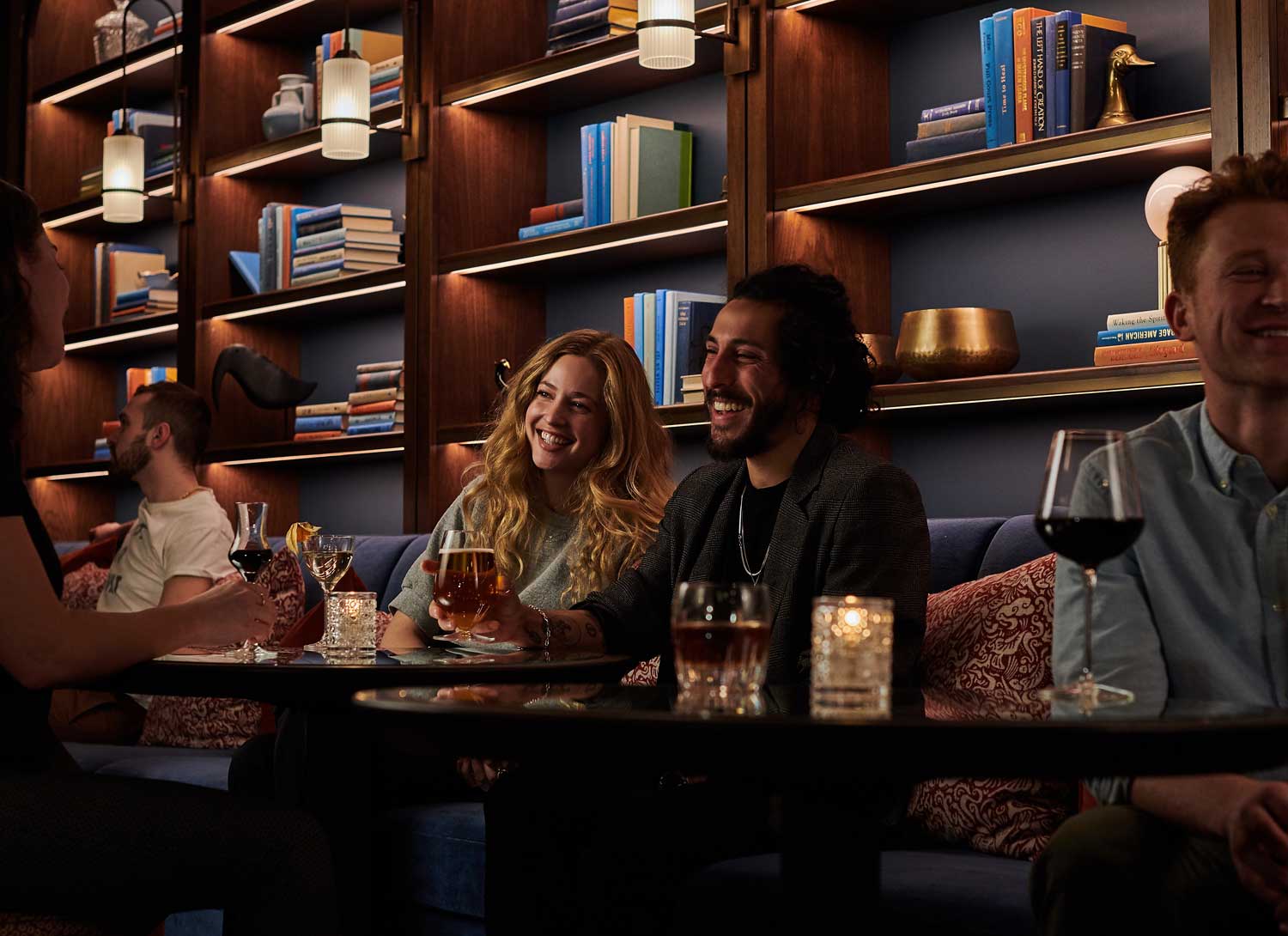 Happy guests sitting at the back of the bar, drinking cocktails and beer