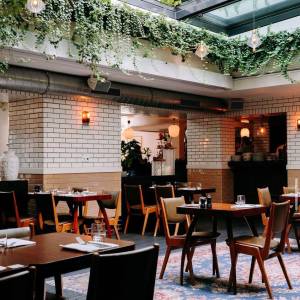 Empty tables in the restaurant, showing the glass roof above and lots of plants around it