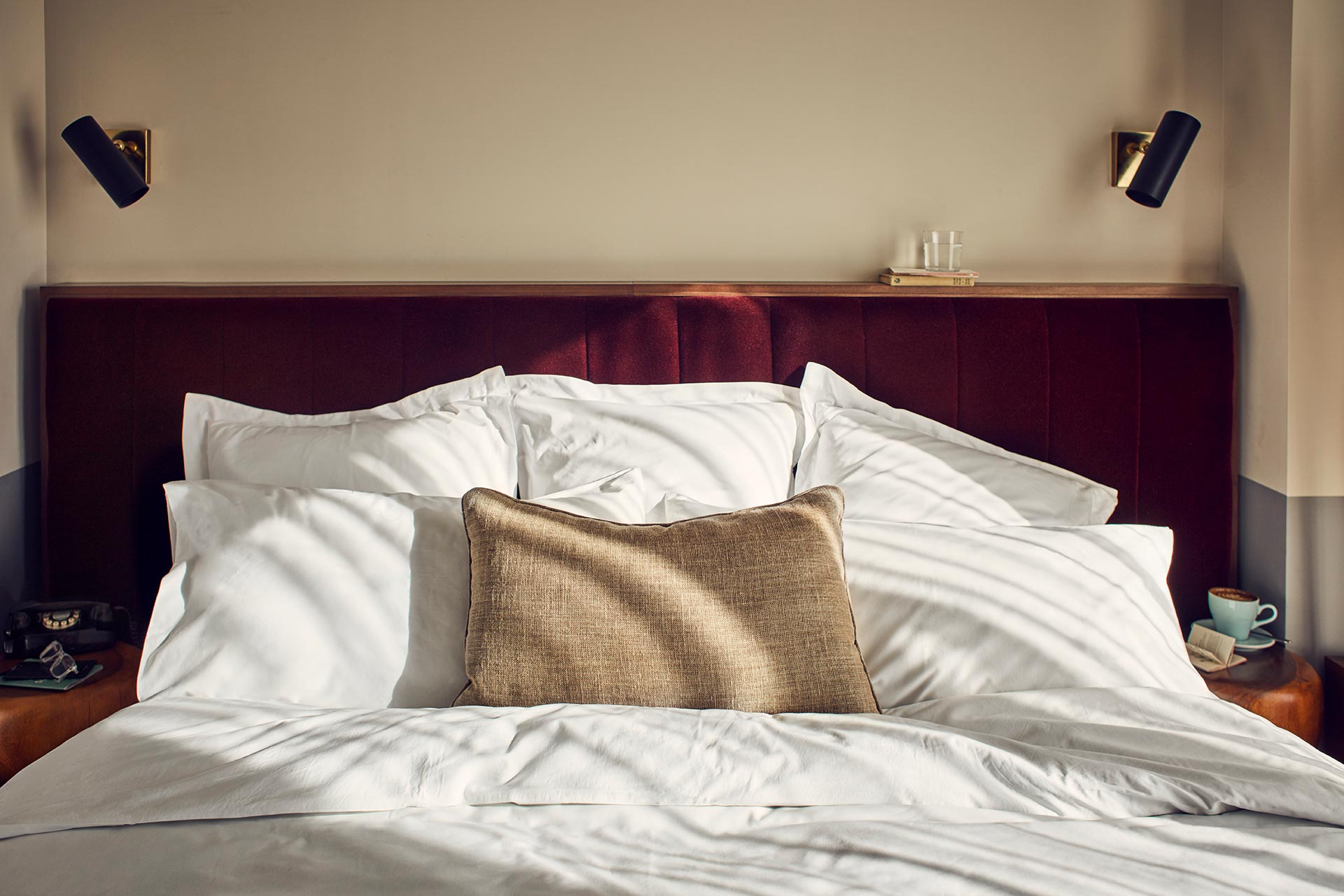 Comfortable bedspread with six pillows and dark wood headboard.