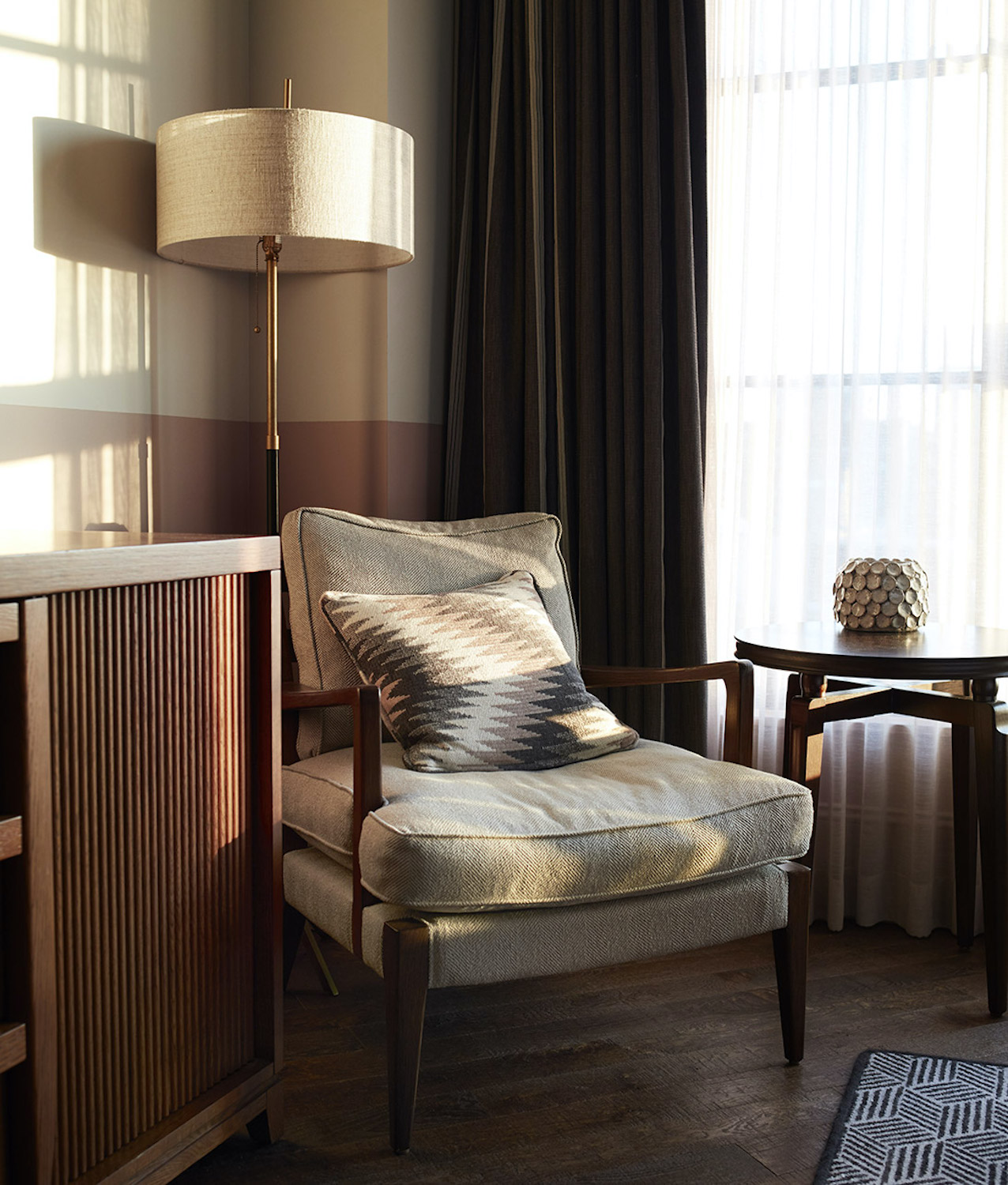 Comfortable lounge chair, table and tall lamp in the corner of a hotel room