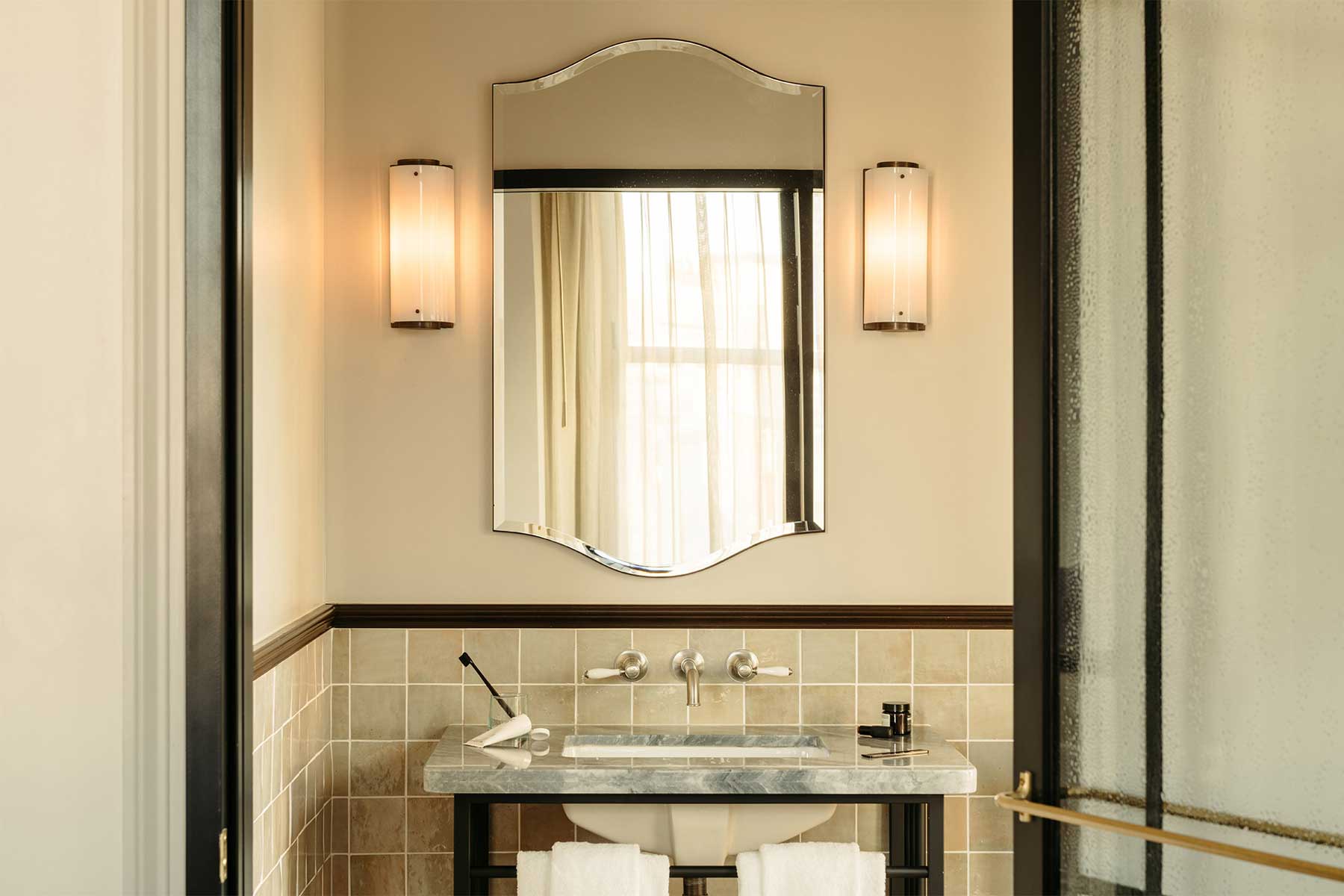 Large mirror on the wall in the bathroom with lights either side, above the sink