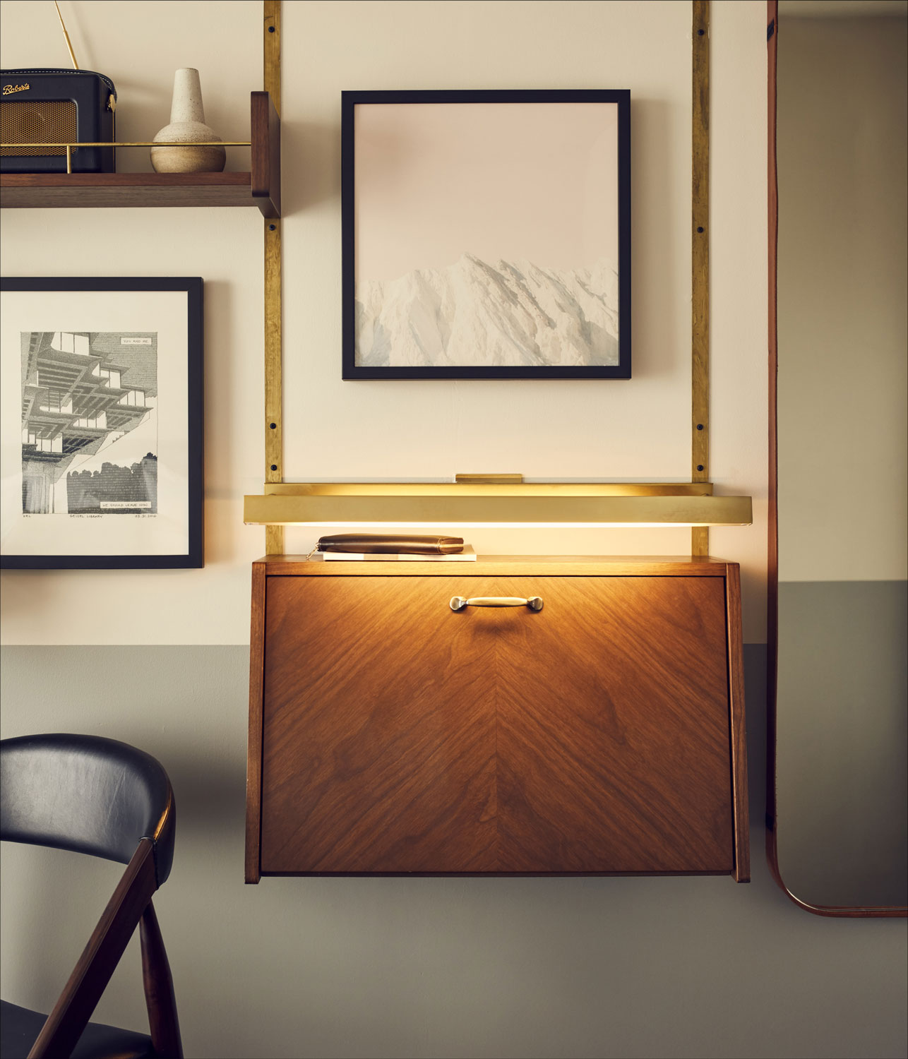 The fold-out bureau desk sits on the wall amongst artwork and shelving