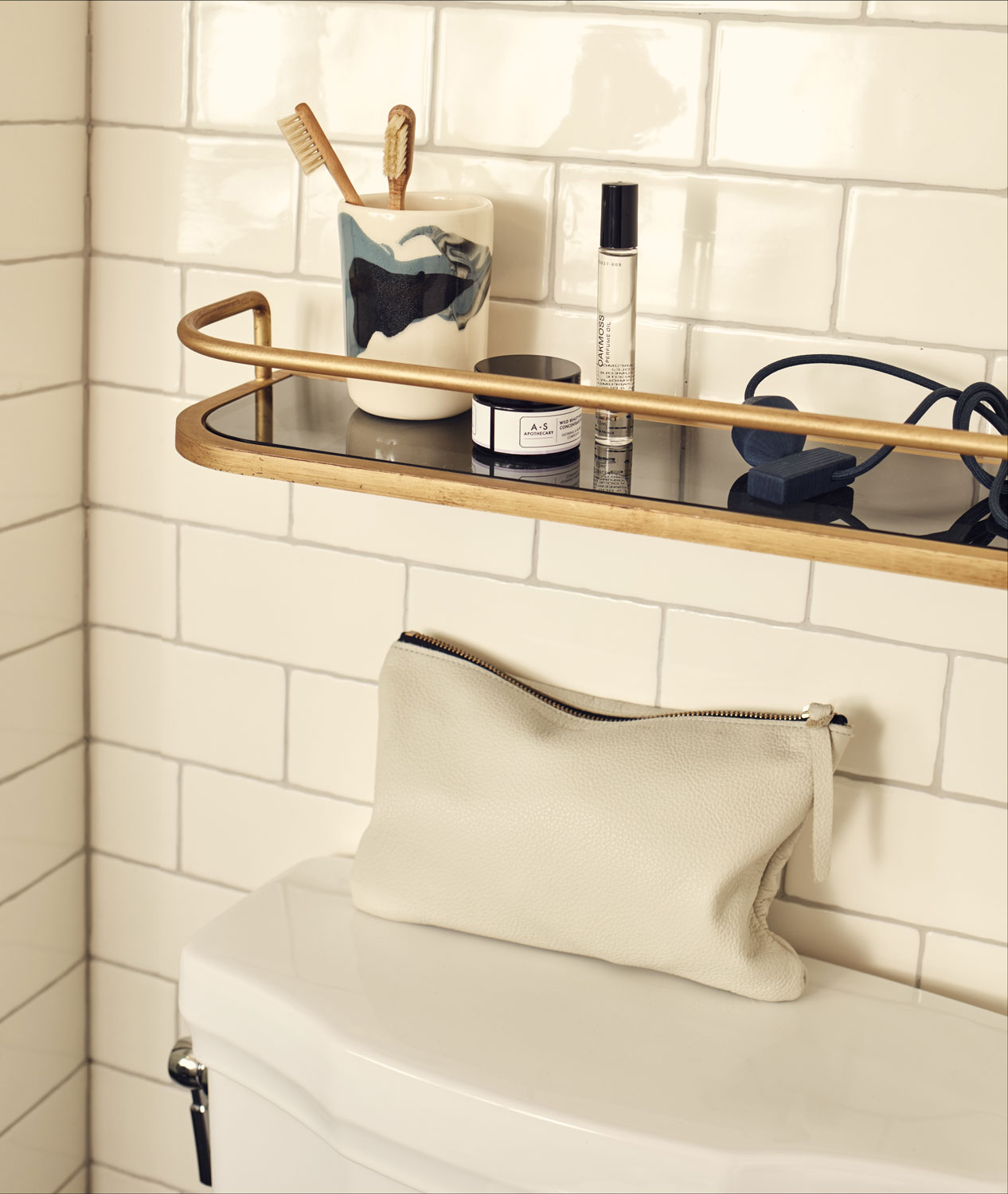 A gold shelf sits above the toilet, the perfect place to put toiletries