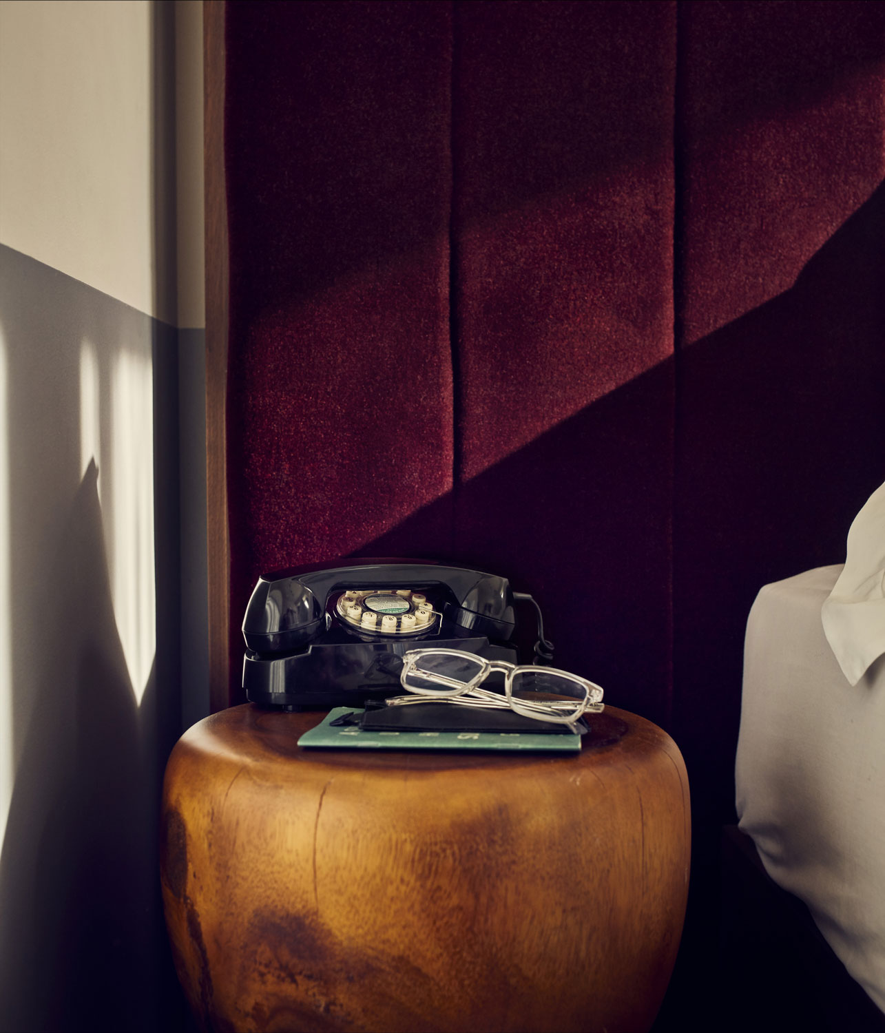 An old fashioned black telephone beside the bed, for calling for room service