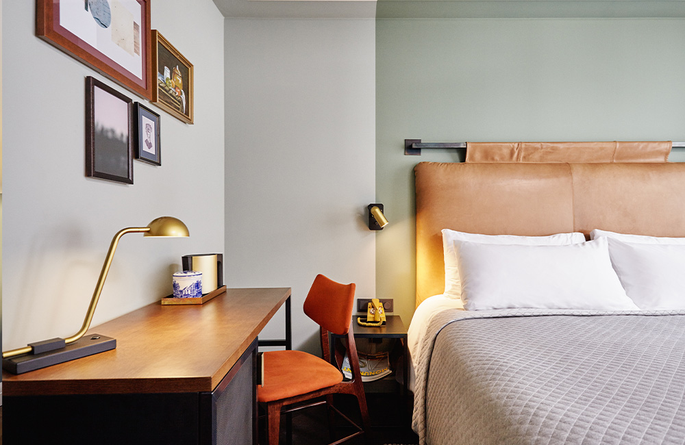 Cosy room showing a headboard, and small desk and a chair next to it.