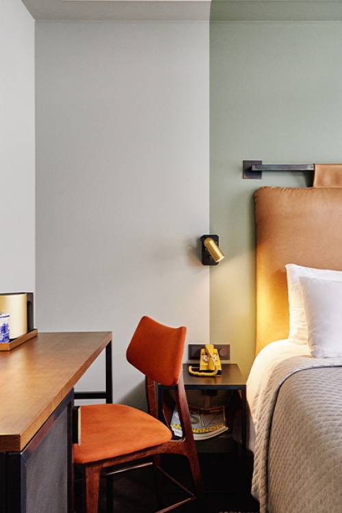 Cosy room showing a headboard, and small desk and a chair next to it.