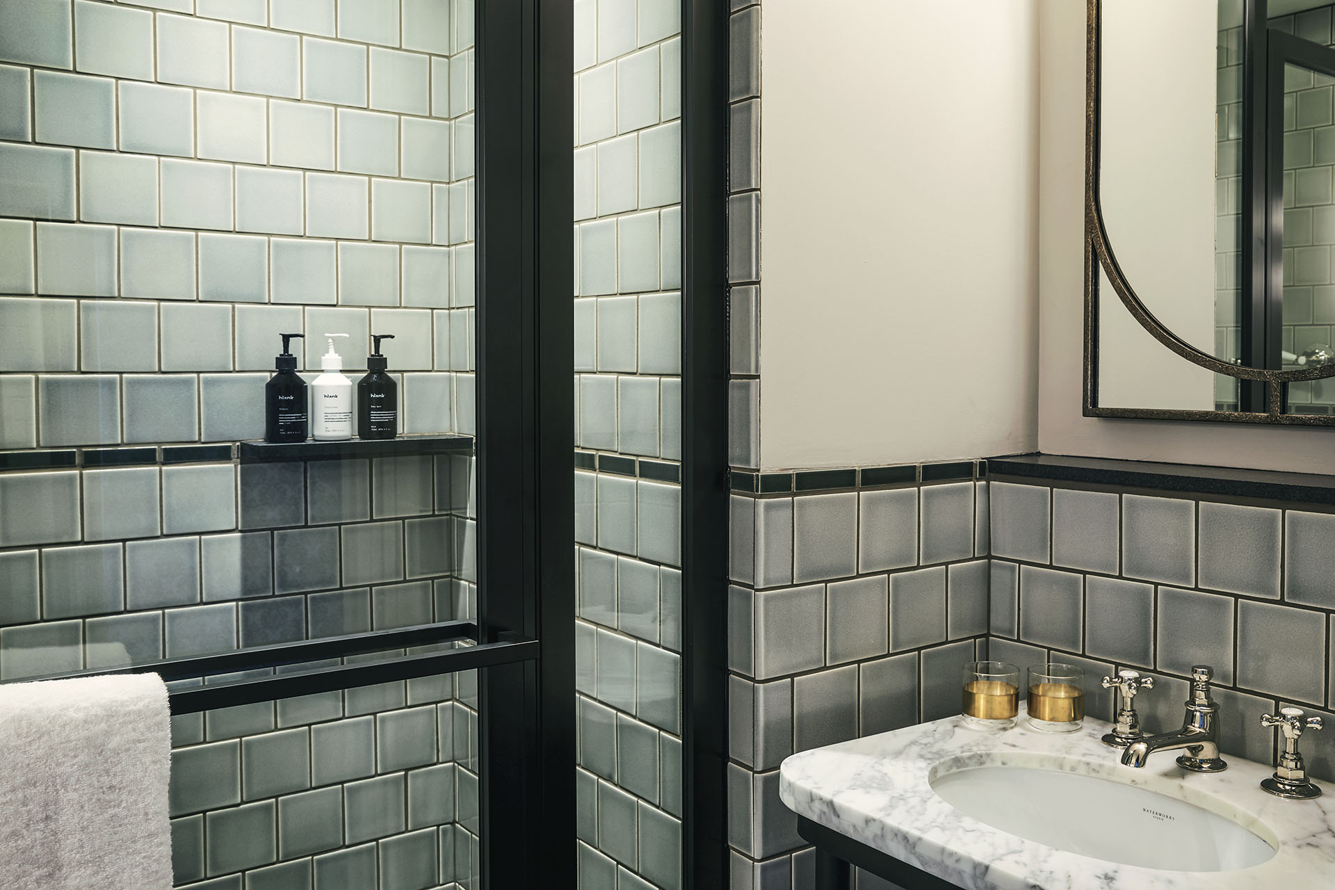 The bathroom has very pale blue-green tiles, with shower gel, shampoo and condition provided in the shower