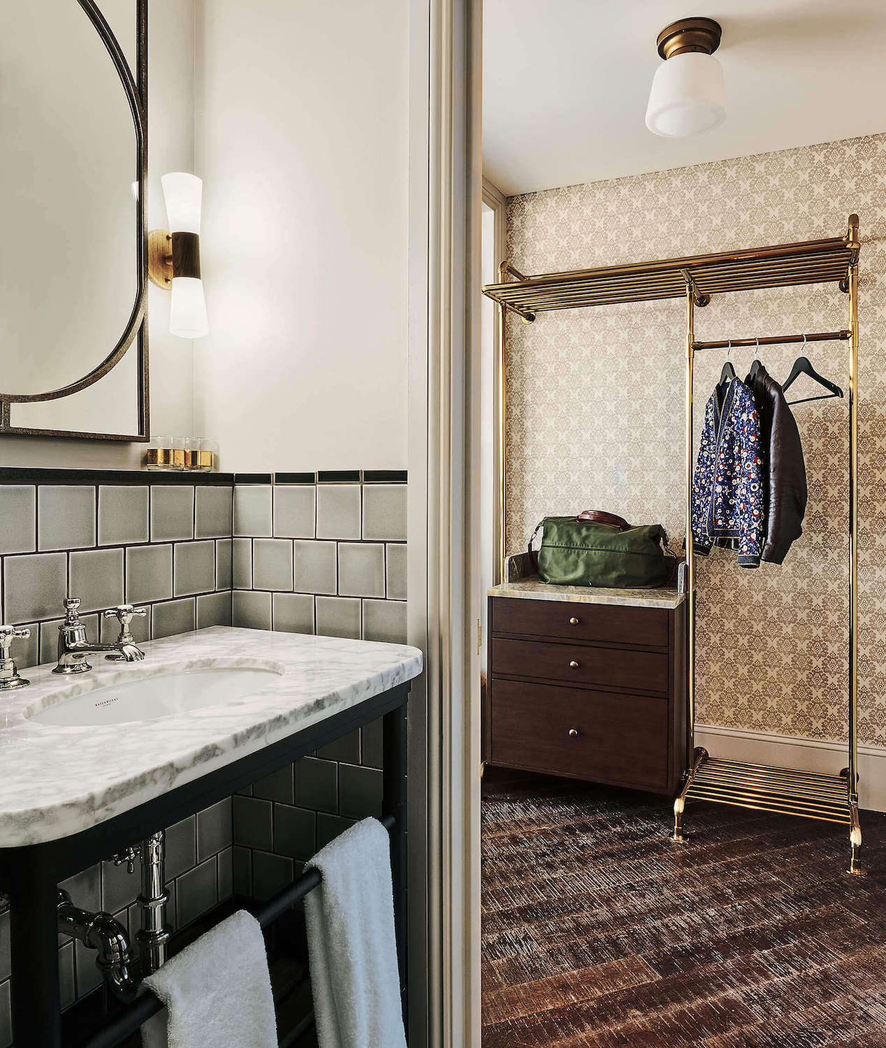 Photo taken from inside the ensuite bathroom, showing the sink and mirror but also the area outside of the bathroom for hanging up clothes