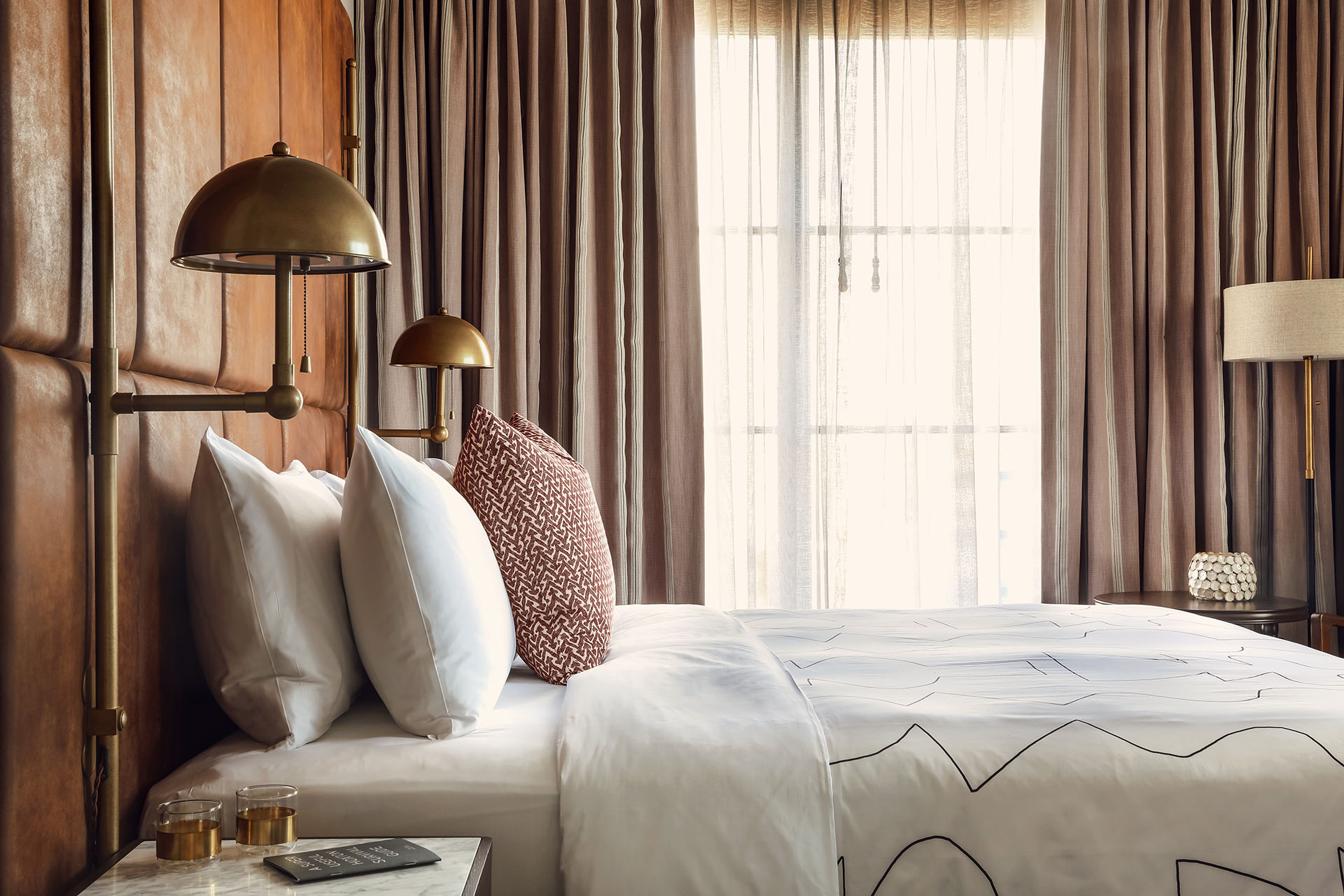 Bed from the side, showing very plump pillows and natural light coming in from the window