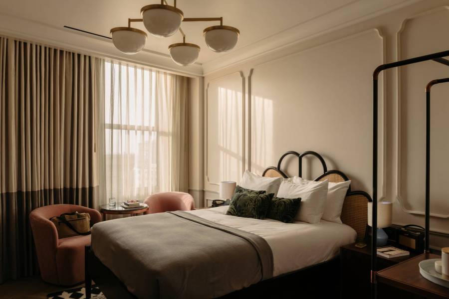 Cosy King room featuring a king-size bed, two soft pink velvet chairs next to a large window, and a table