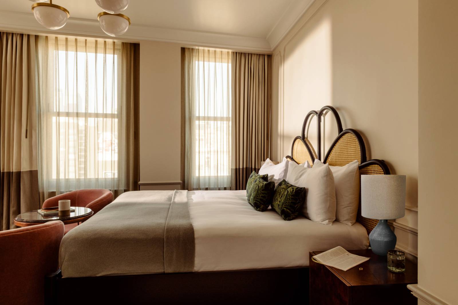 Biggy room at The Hoxton, Downtown LA hotel showing a king sized bed, a bedside table, and seating.