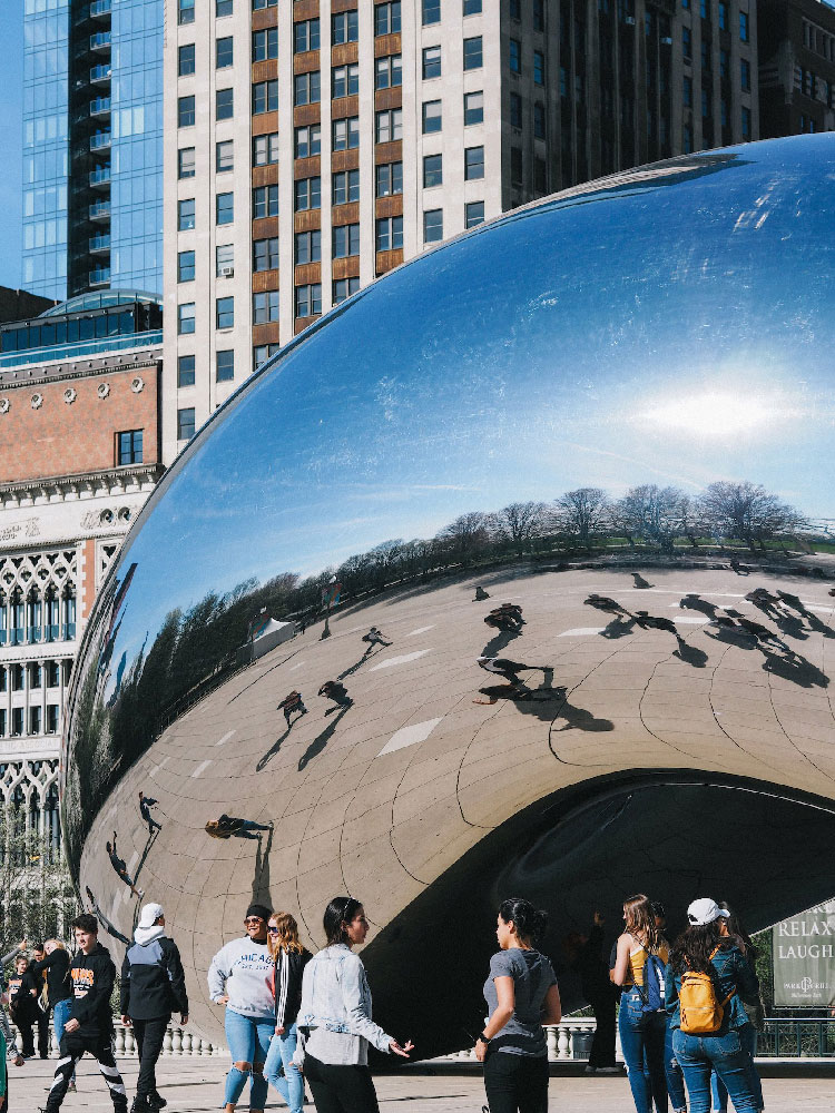Reflections of people standing beneath The Bean