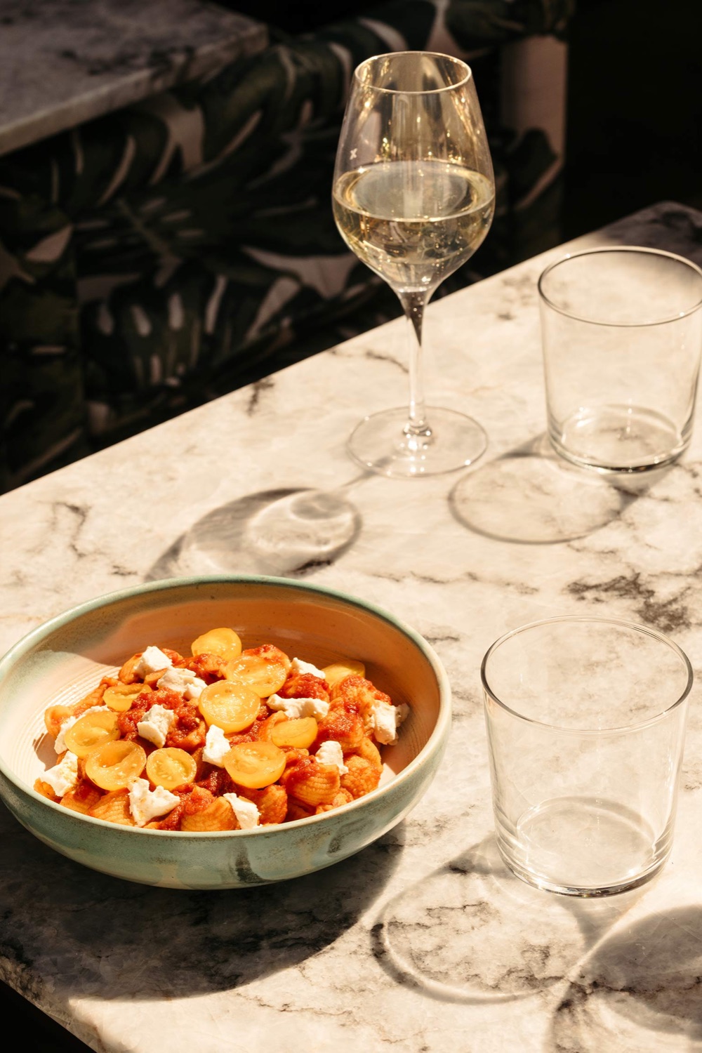 A bowl of food and wine glass on a table
