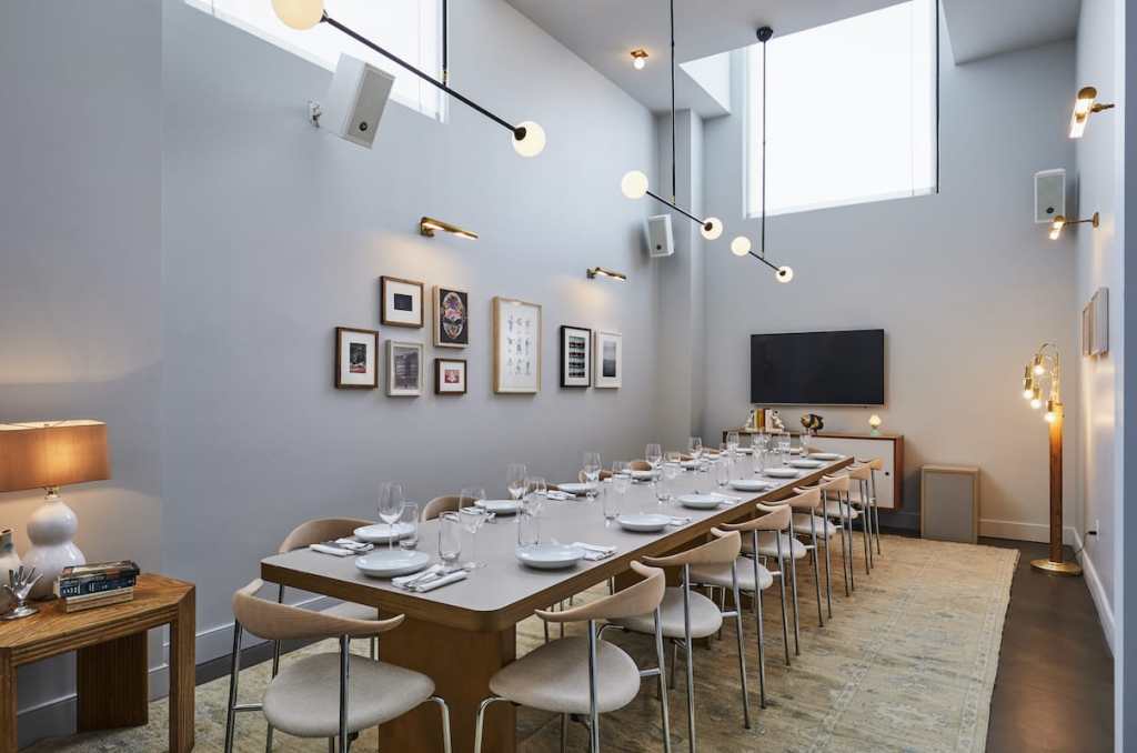 A long table seating 16 people, with plates and glasses ready for dining