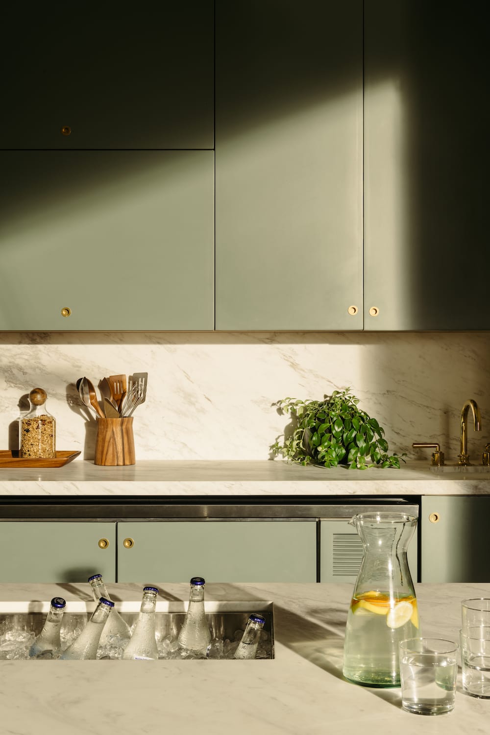 Glass water bottles resting in ice in a sink in the Pantry kitchen