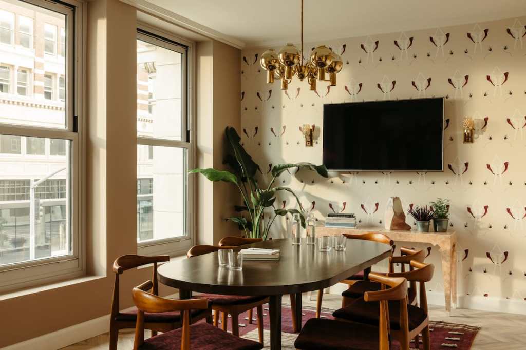 The room has two large windows and is set up for a meeting for eight people