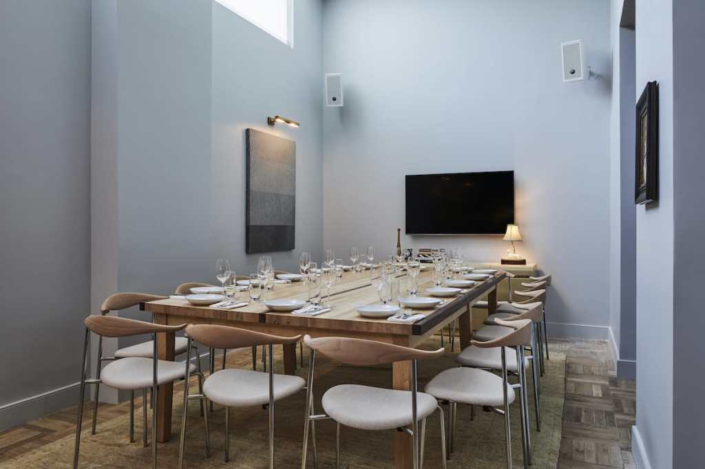 A large table, with 16 seats around it, each with plates and glassware ready for dining