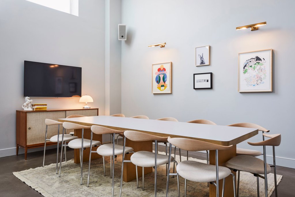 A long table with 12 chairs around it, with a TV on the wall at one end of the room