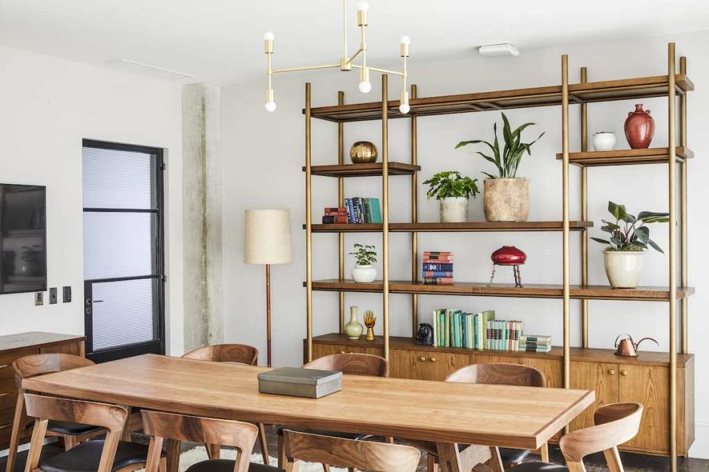 Each room has the same shelving cabinet on one wall, which has lots of decorative vases, plants and books