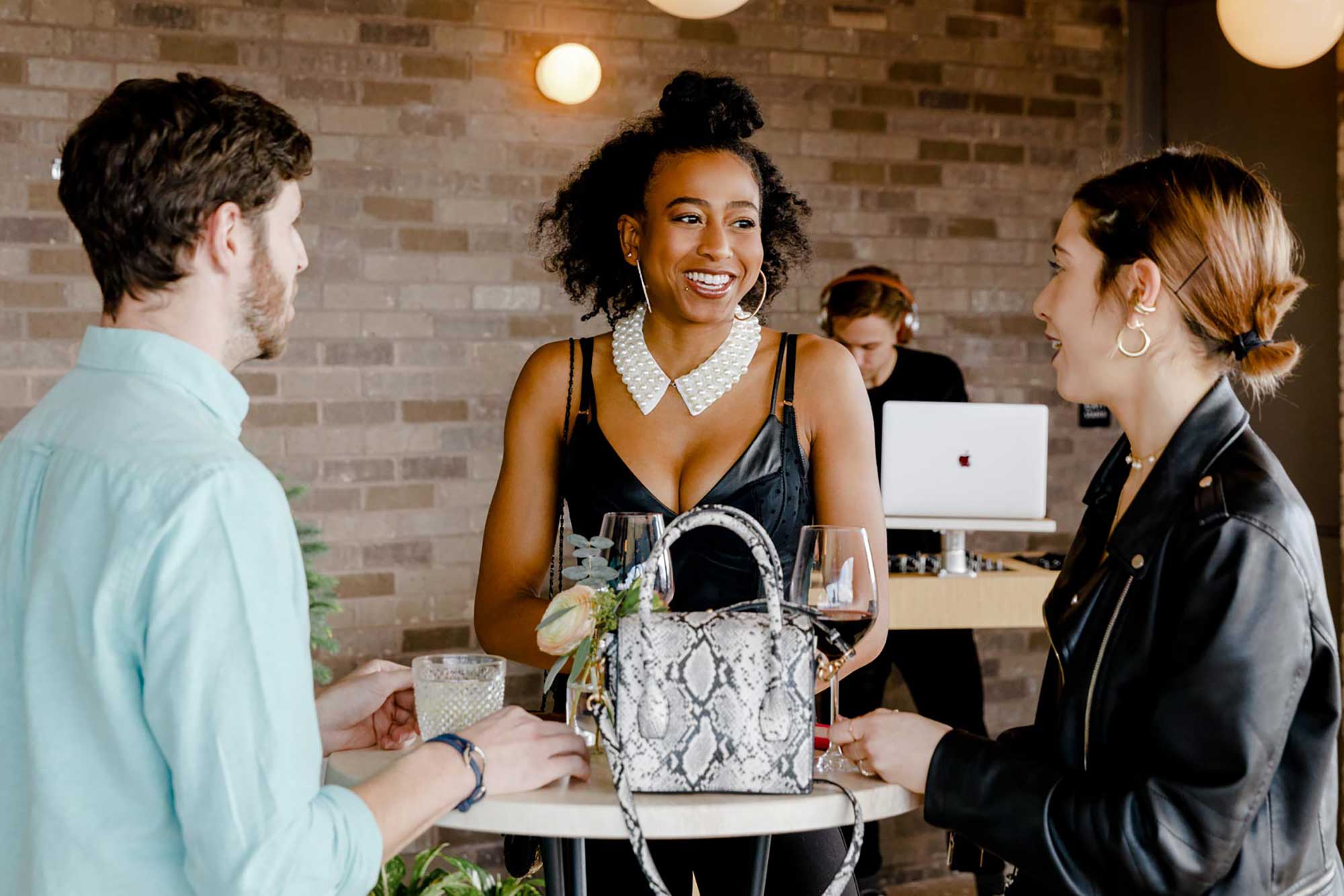 Three people enjoy drinks with DJ in the background
