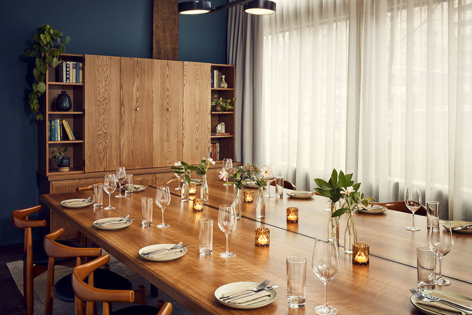 Room suitable for a large party of dining guests, with flowers and candles on the table