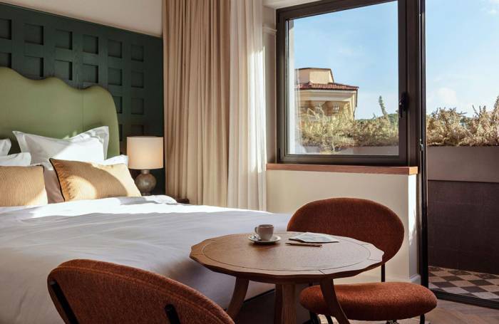 Blue sky is shown outside of the hotel room, which has a small balcony