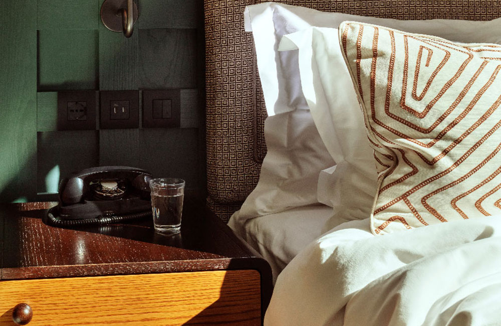 A telephone and glass of water on the bedside table