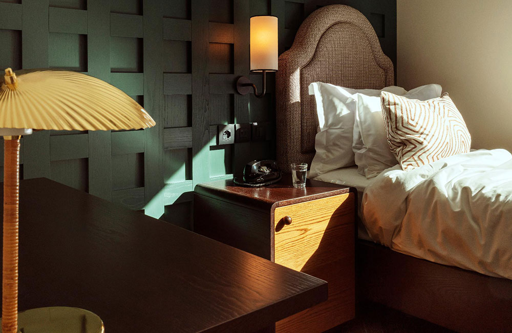 Single bed with dark green wood panelling behind it