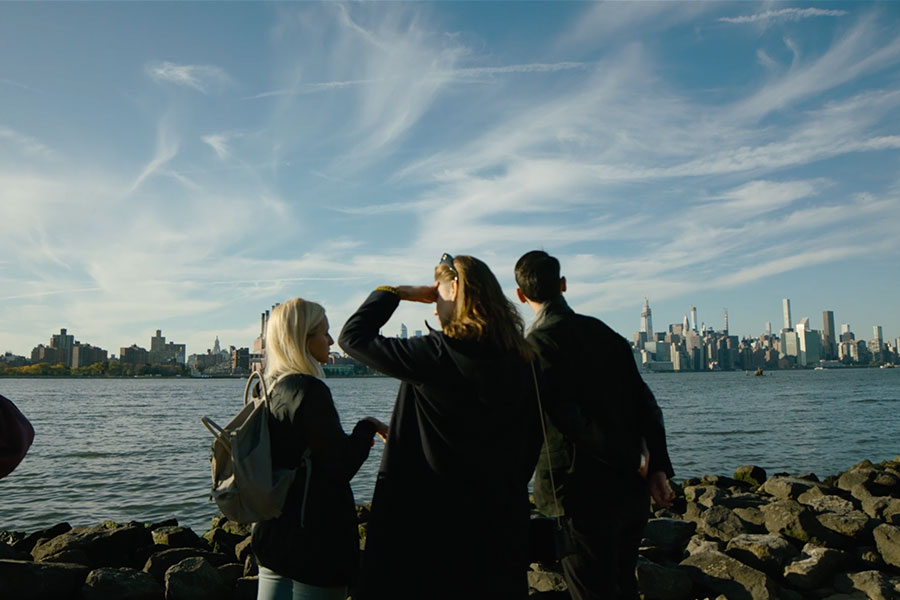 Three people looking at the city across the river