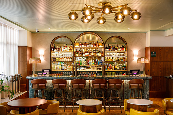 View of the bar with mirror shelfs and bar stool along the counter.