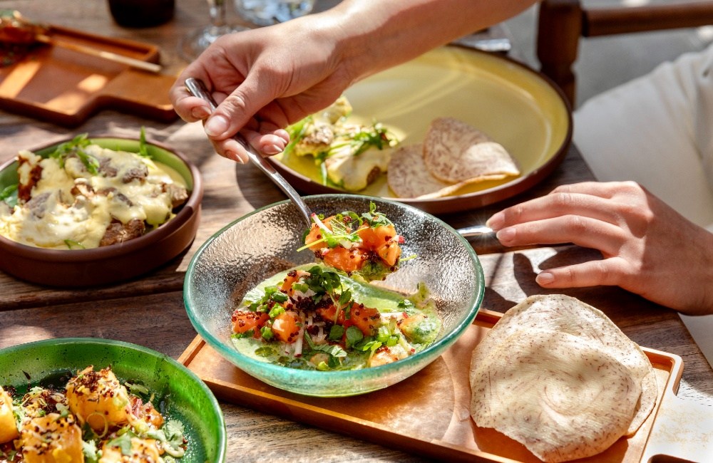 Vibrant green dish served in a deep clear glass bowl, accompanied by other dishes and bread on the table.