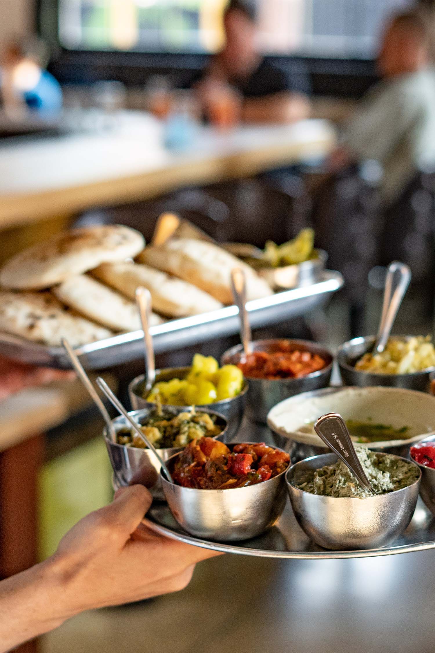 A waiter carrying two platters of meze and breads