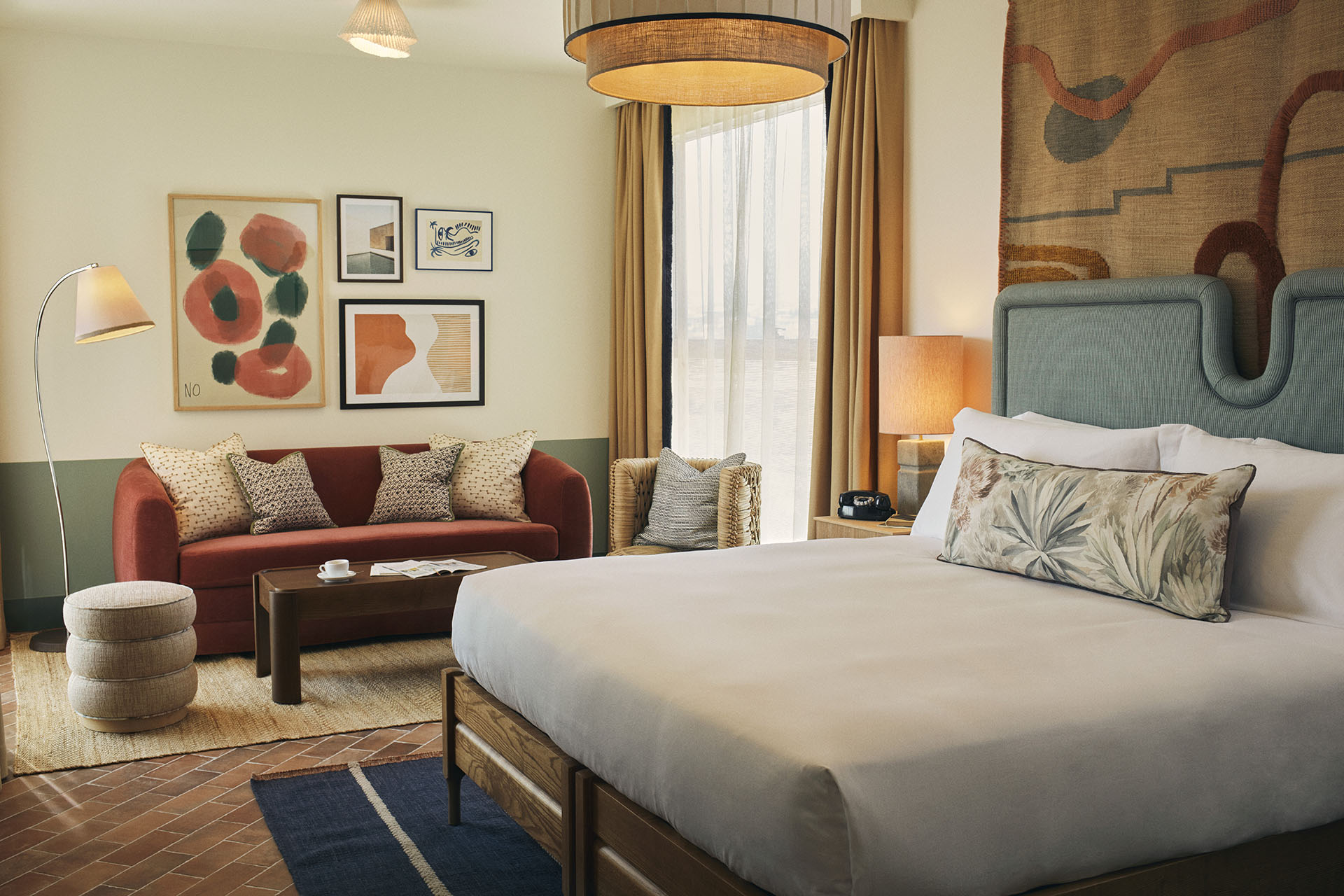 The hotel room has a large double bed and a lounge area with sofa and two chairs