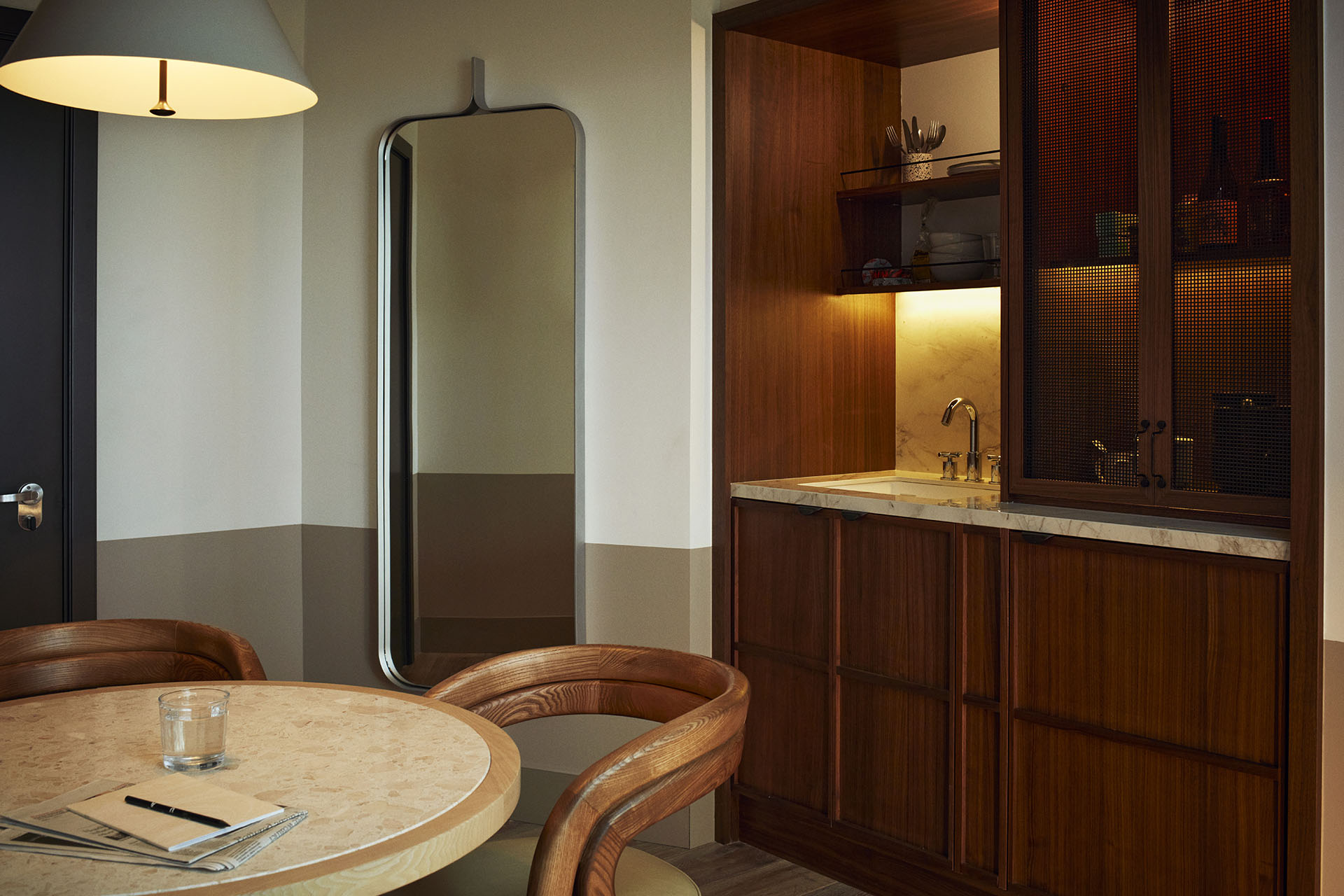 There is a pantry with dining table, sink and cupboards, and a full length mirror on the wall