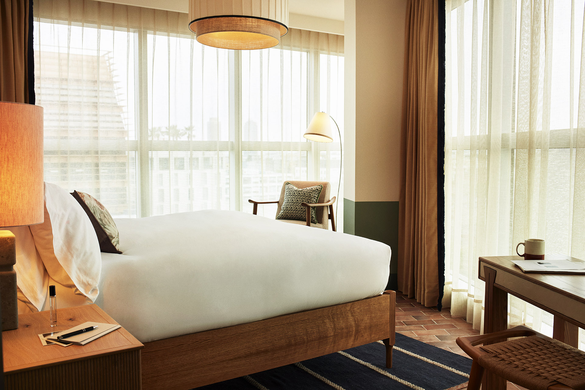 The bedroom has floor to ceiling windows on two adjacent walls, with lots of natural light