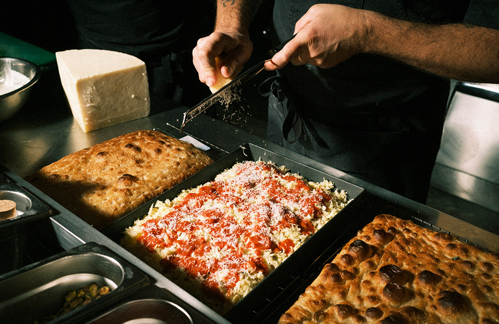 Chef grating cheese over a deep dish pizza
