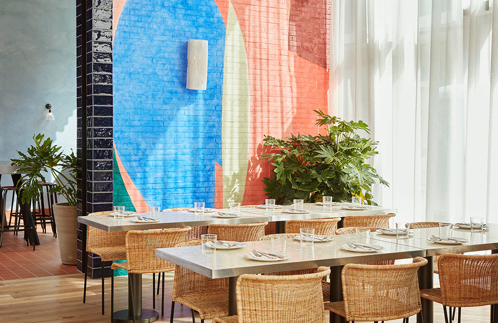 Colourful wall with pastel colours behind tables set for 8 people