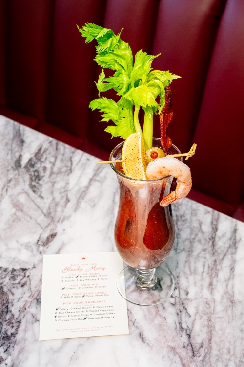 Elevated Bloody Mary garnished with celery, lemon, olive, and a shrimp.