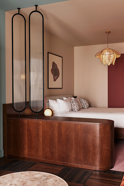 Interior of a Brussels bedroom showing wall art, wooden wardrobe, glass partition and comfortable bed.