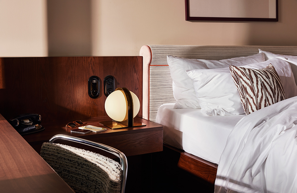 A bedside with artistic spherical lamp next to plush pillows on a soft mattress at our hotel in Brussels