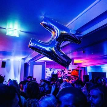 Inflatable H carried aloft in a room lit for dancing