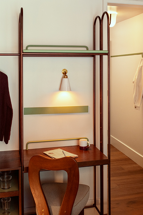 Open wardrobe with shelves and jacket hung up plus chair with polished wooden frame.