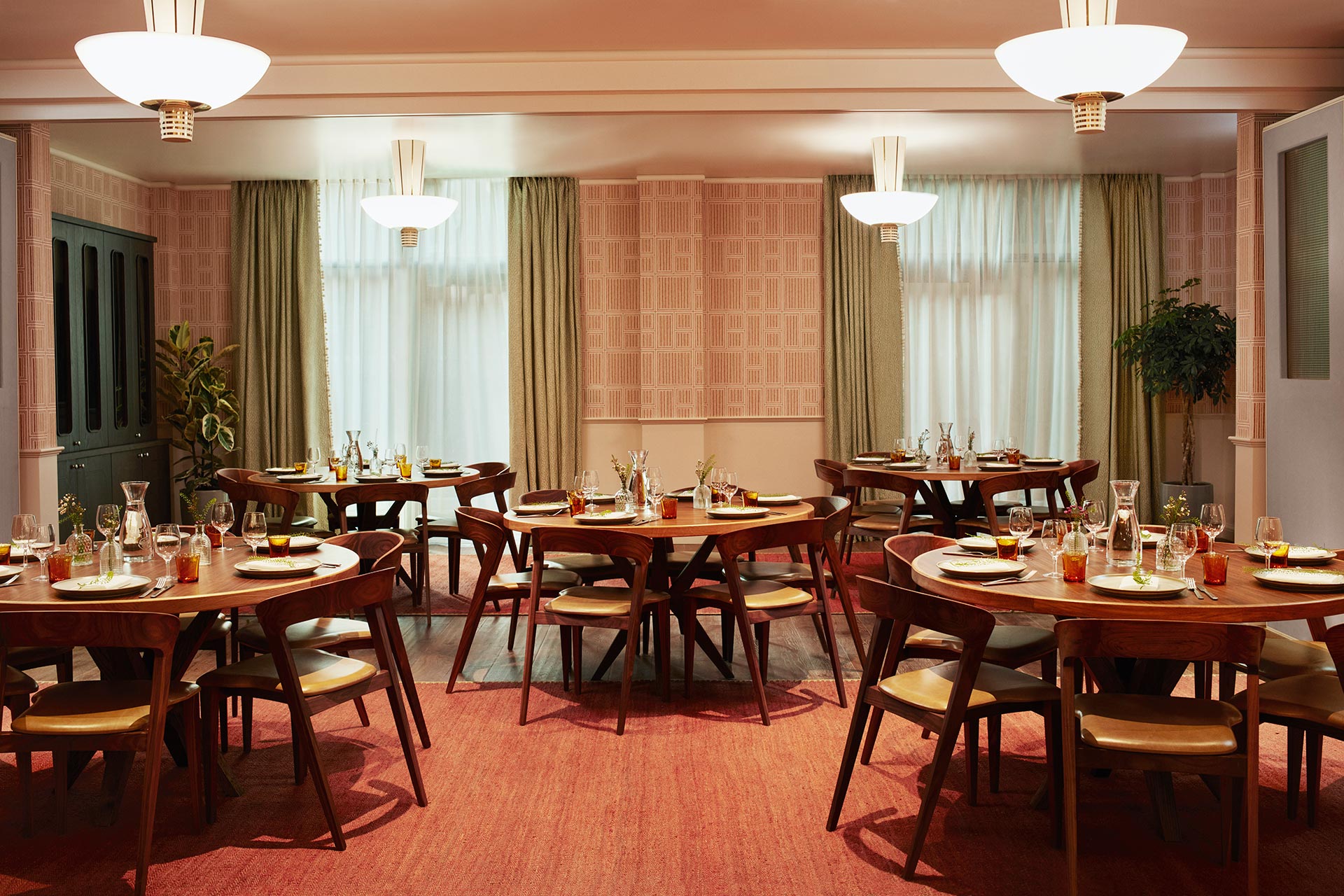 Round wooden tables with stylish cushioned chairs arranged for a meal in a well-lit room.