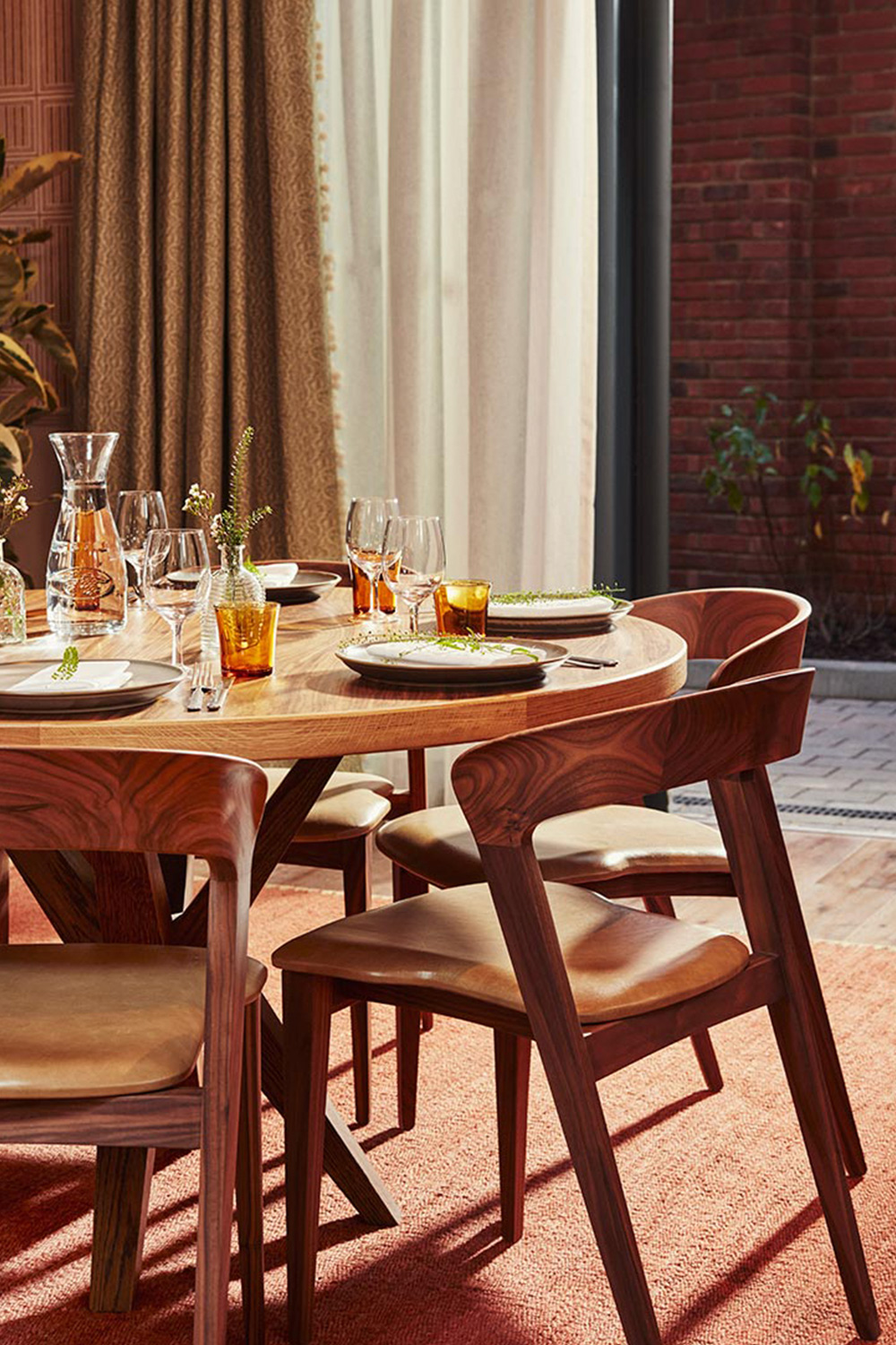 Stylish wooden chairs around a table laid for a meal.