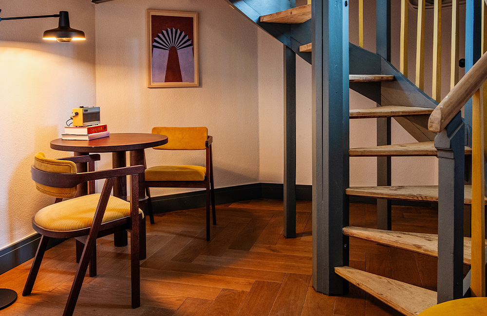Underneath the staircase, two yellow chairs and a table create a cozy space.